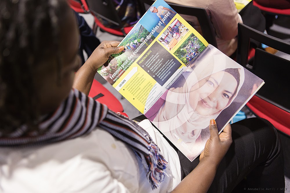 Person reading a brochure featuring images and text on economic empowerment.